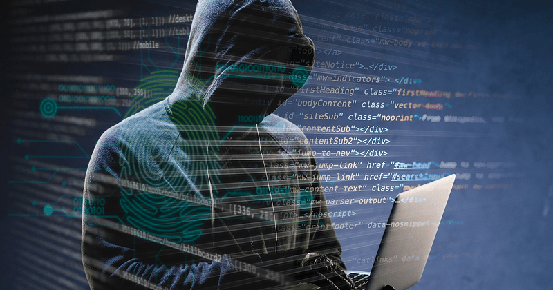 A hooded figure using a laptop, with digital code and fingerprint graphics overlaid, symbolizing cyber threats.